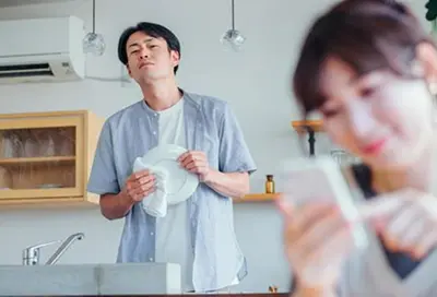 スマホを見る妻を覗く夫の写真