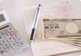 お金と電卓と家計簿の写真